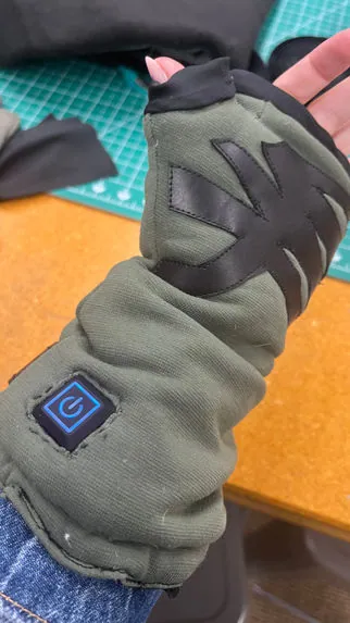 Olive heated cuff with a power button on the back of the hand